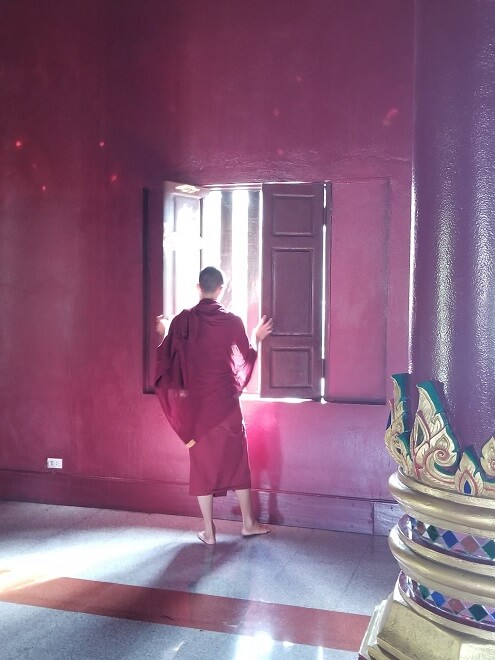 monk opening window Wat Rajamontean Chiang Mai